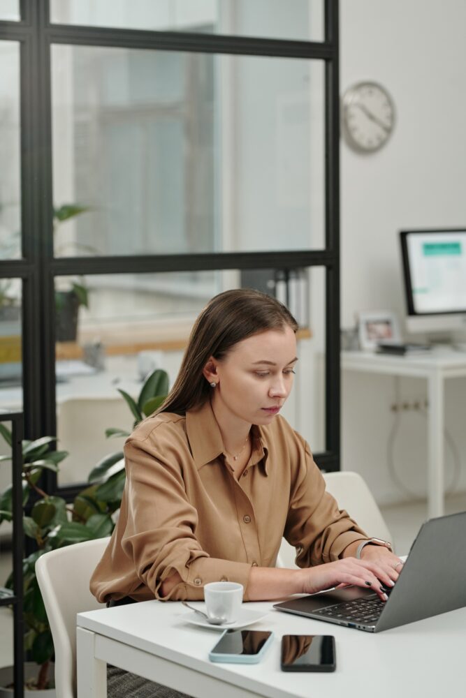 A lady Typing on Laptop Keyboard Sitting at Office Workplace